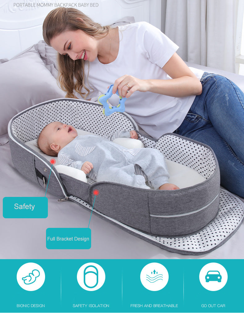 Maman qui joue avec le bébé dans son couffin de voyage